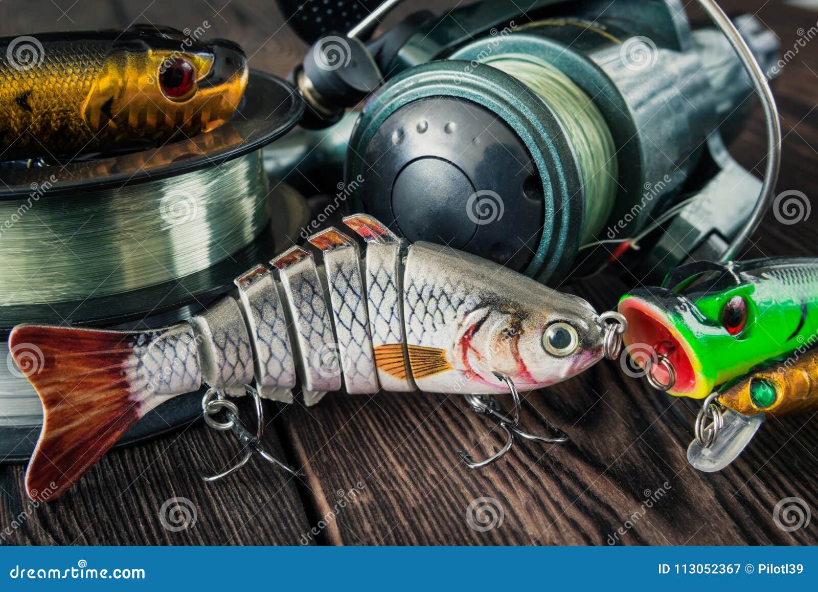 https://thumbs.dreamstime.com/z/lures-fish-spinning-baits-wobblers-poppers-coils-fishing-line-spool-wooden-background-113052367.jpg