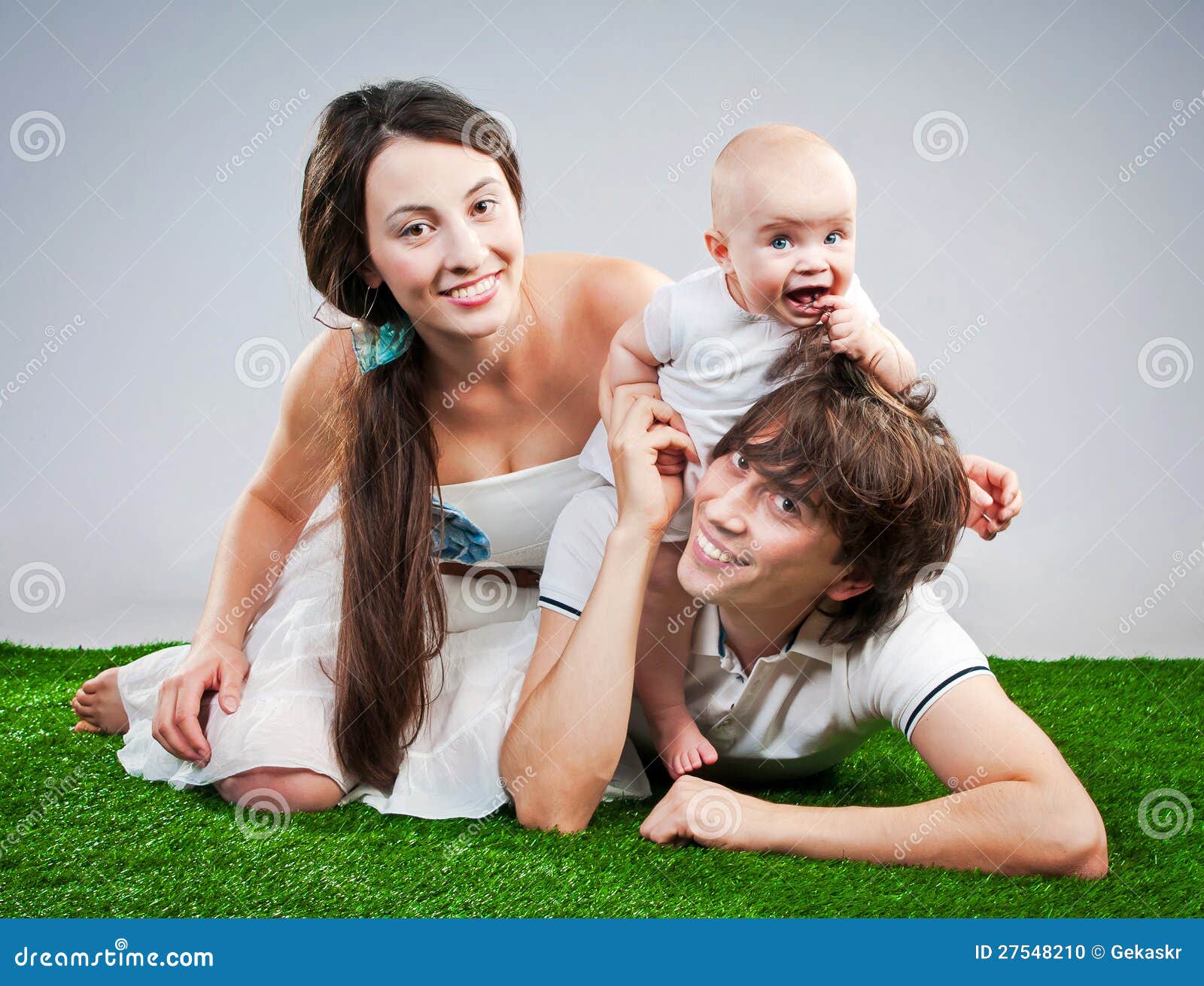 Lycklig familj som ler på ett grönt gräs