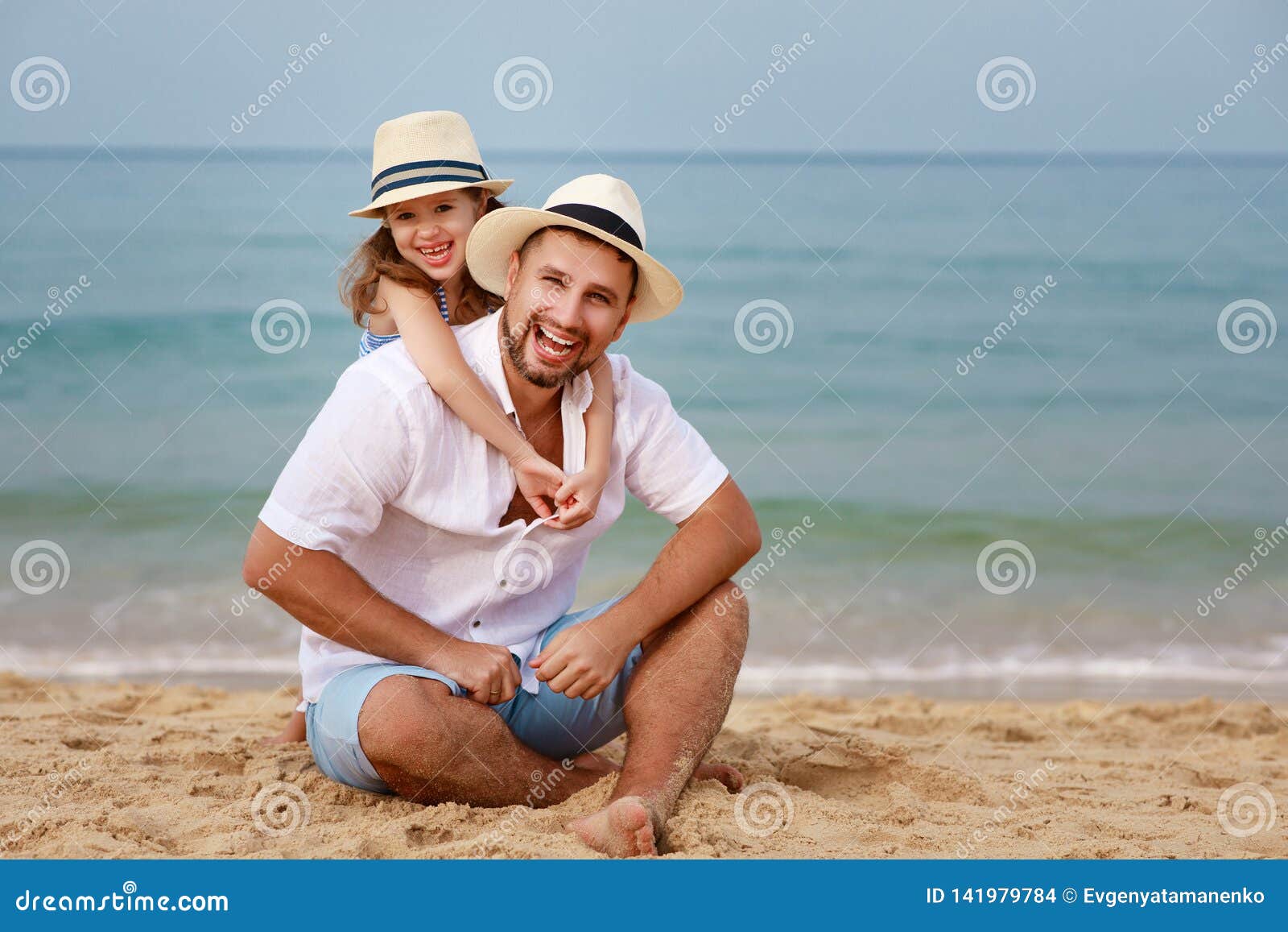 Lycklig strandfamilj fader- och barndotterkram på havet