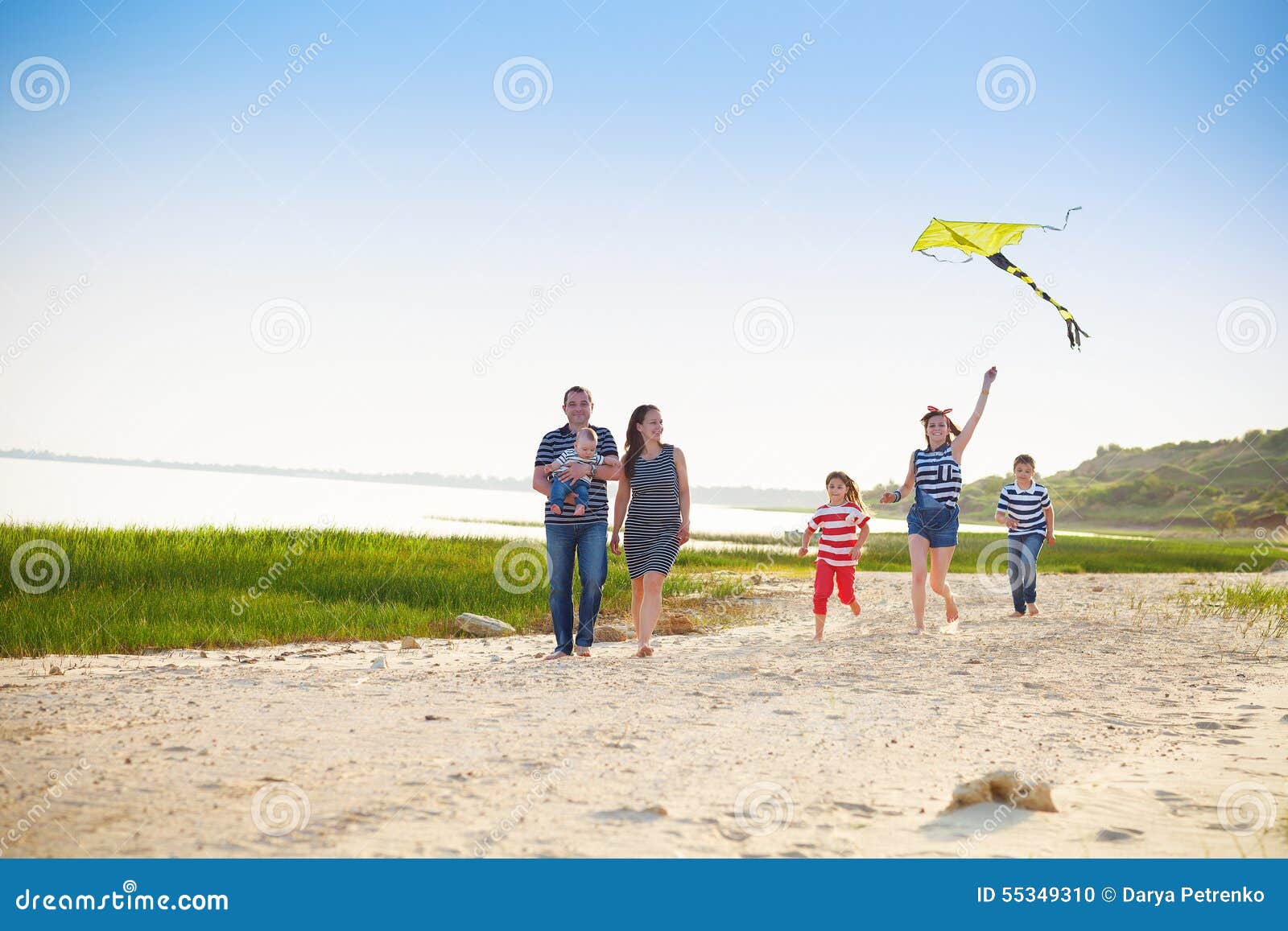 Lycklig ung familj med att flyga en drake på stranden för sommarterritorium för katya krasnodar semester