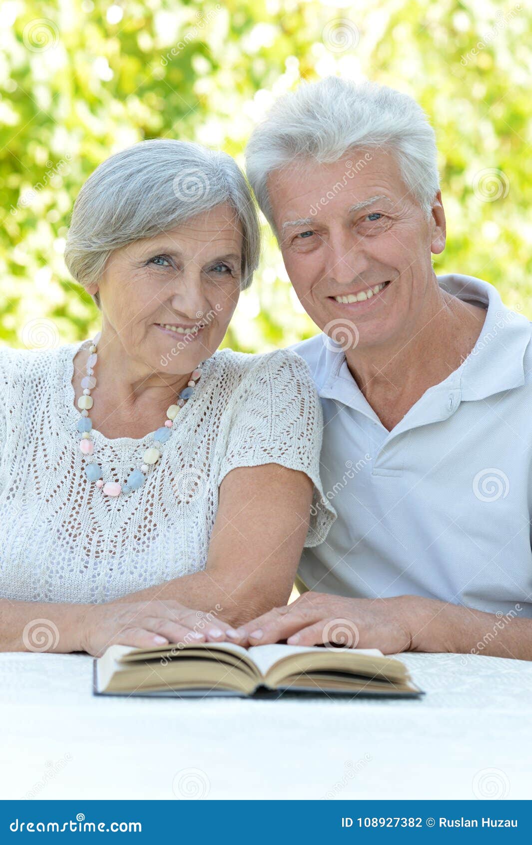 Härliga lyckliga gamla par med boken i sommar