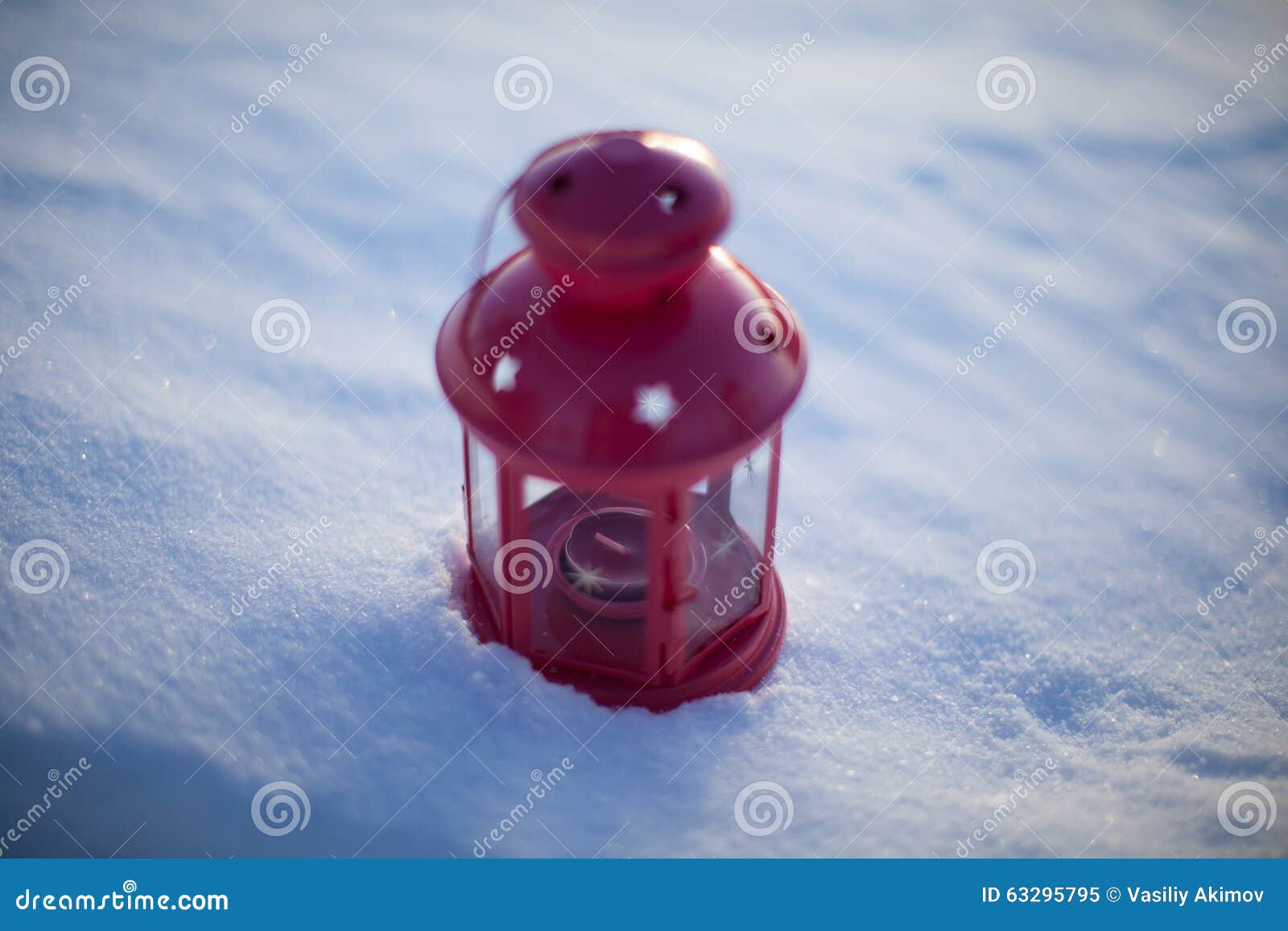 Lámpara roja en nieve. Linterna roja con una vela en la nieve