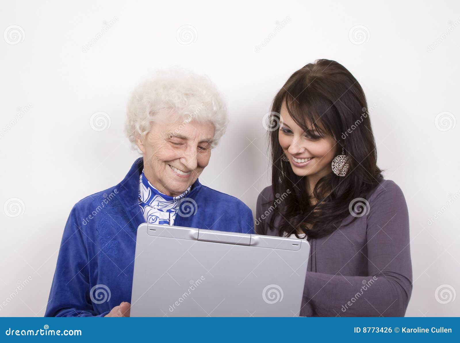 Lächeln am Computer. Eine weiße behaarte Dame und ein Lächeln der recht jungen Frau an, was auf einem Laptop ist.