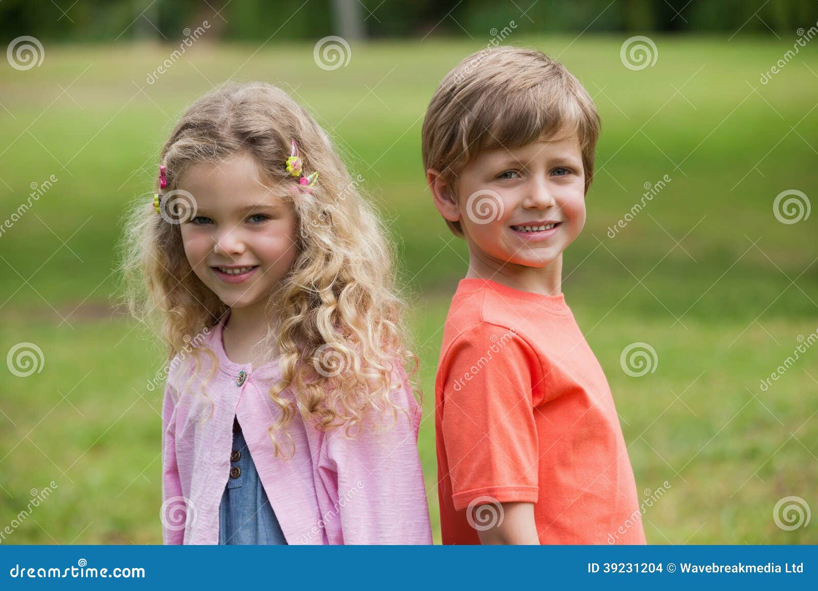 Lächelnde Kinder, die am Park stehen. Porträt von zwei lächelnden Kindern, die am Park stehen
