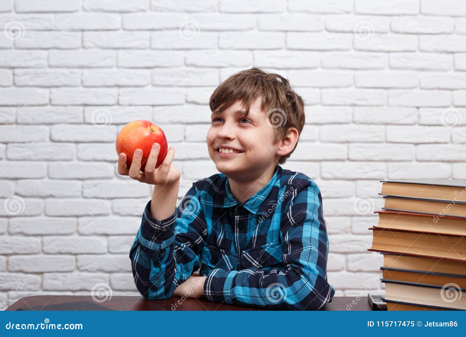 Lächelnder netter Schüler mit großem rotem Apfel Gesunde Ernährung, Schulmahlzeitkonzept