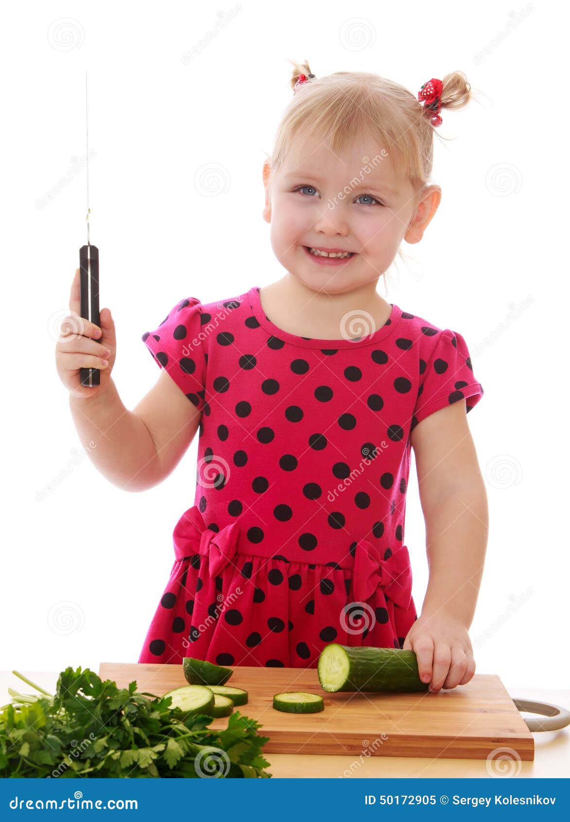 Lächelndes kleines Mädchen mit einem Messer schnitt Gurke Lokalisiert auf weißem Hintergrund, Lotus Childrens Mitte