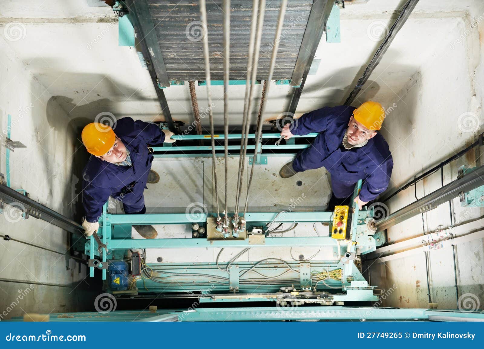 machinists adjusting lift in elevator hoist way