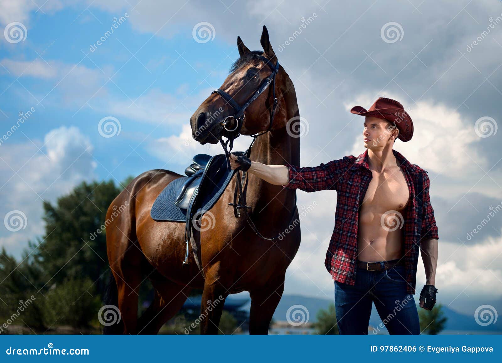 macho man handsome cowboy and horse on the background of sky and water.