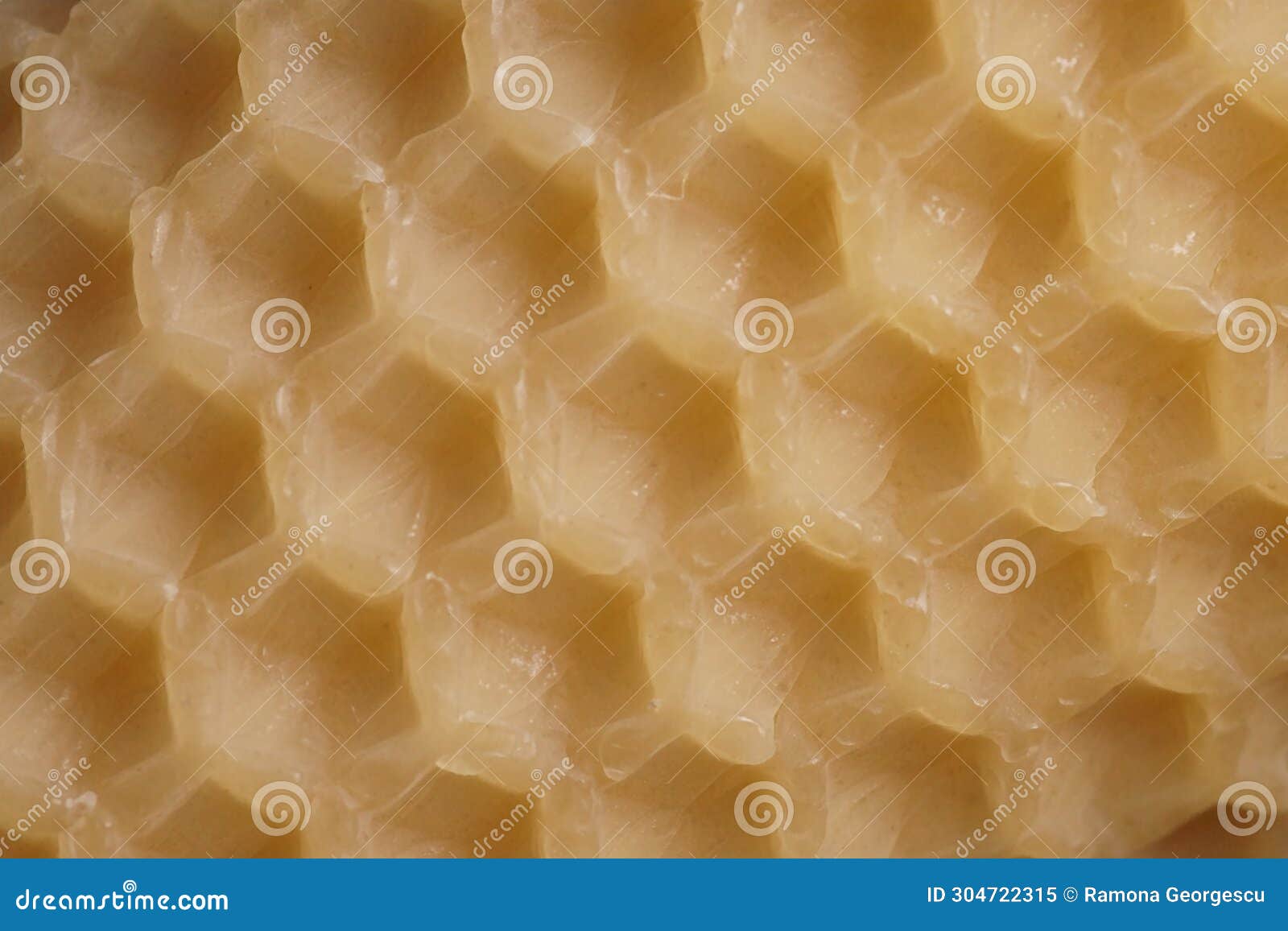 macro background with an old sheet of natural beeswax sheet of comb foundation with a hexagonal pattern cera alba