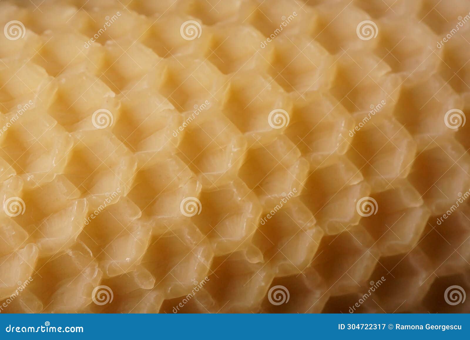 macro background with an old sheet of natural beeswax sheet of comb foundation with a hexagonal pattern cera alba