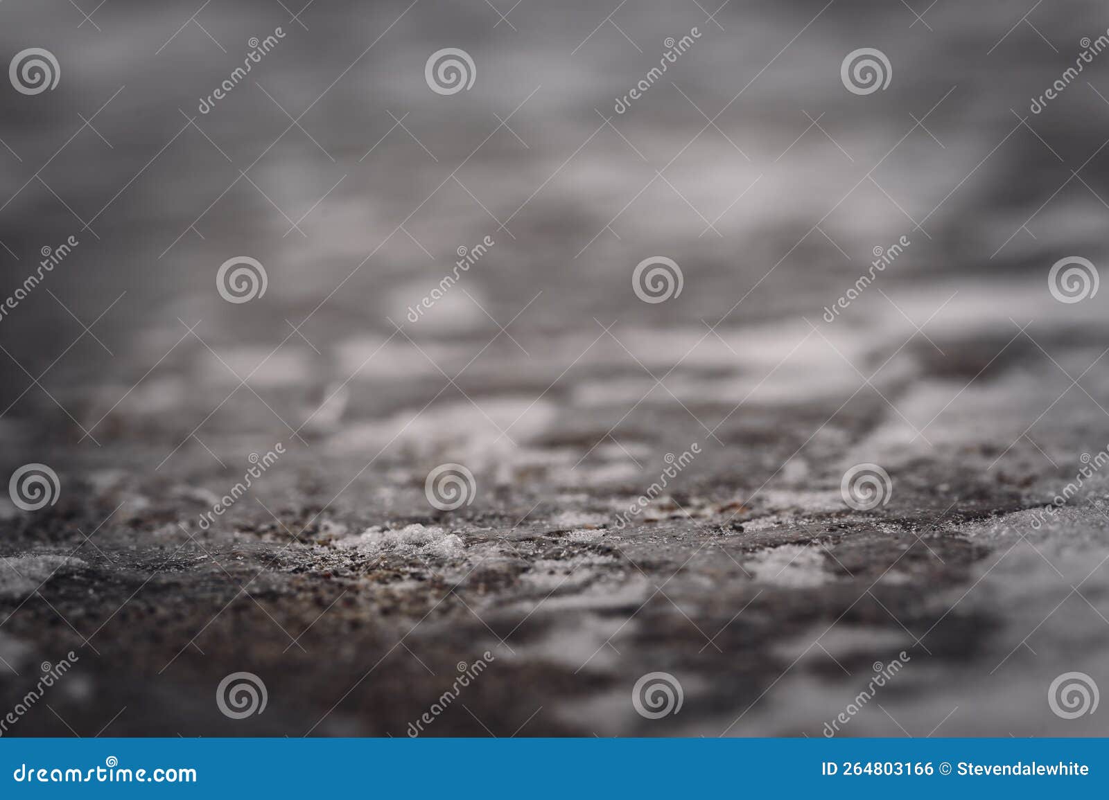 macro ground level closeup view of rock salt ice-melt on concrete with a frozen layer.