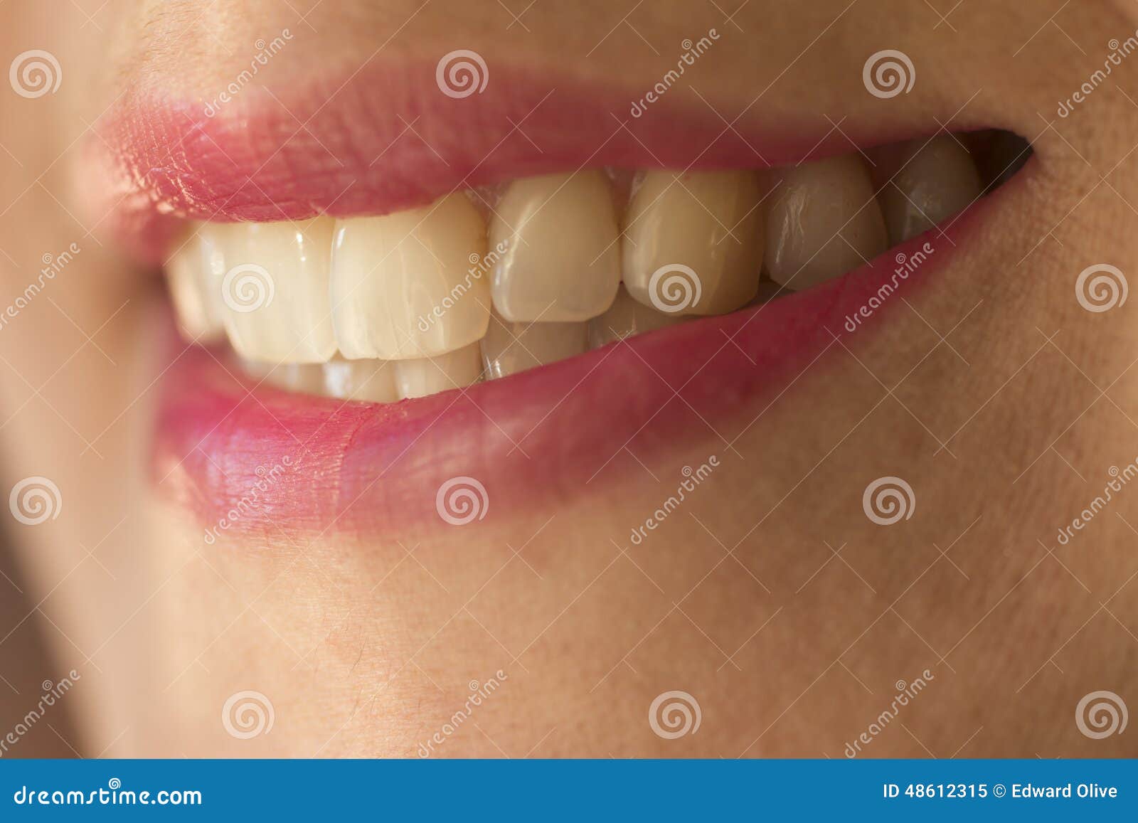 macro shot of female smile with teeth and pink lipstick