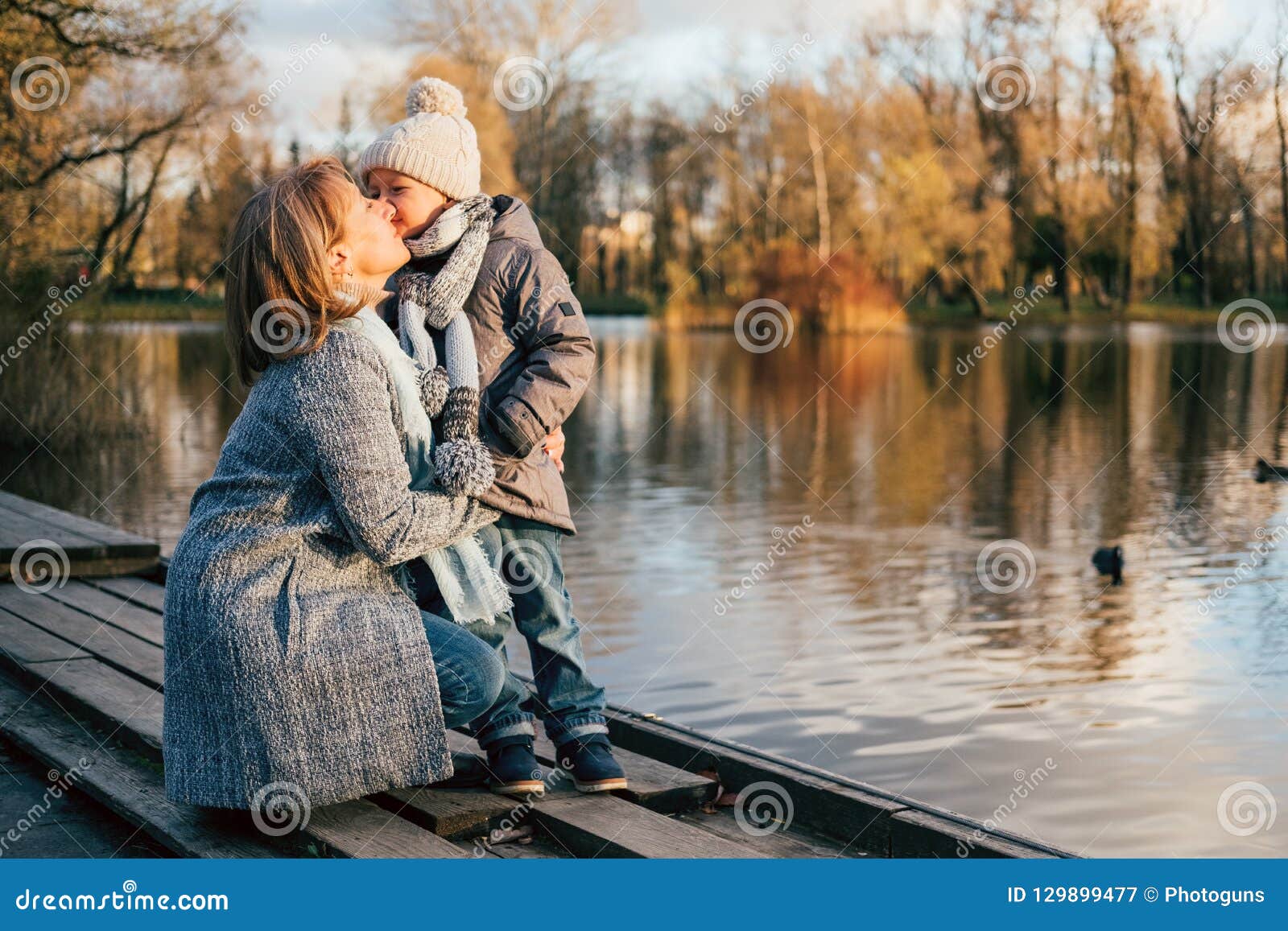 Madre e bambino che abbracciano al parco di autunno vicino al lago Figlio felice con la mamma divertendosi, rilassarsi, godente della vita Il giorno delle madri, famiglia che sveglia sul parco