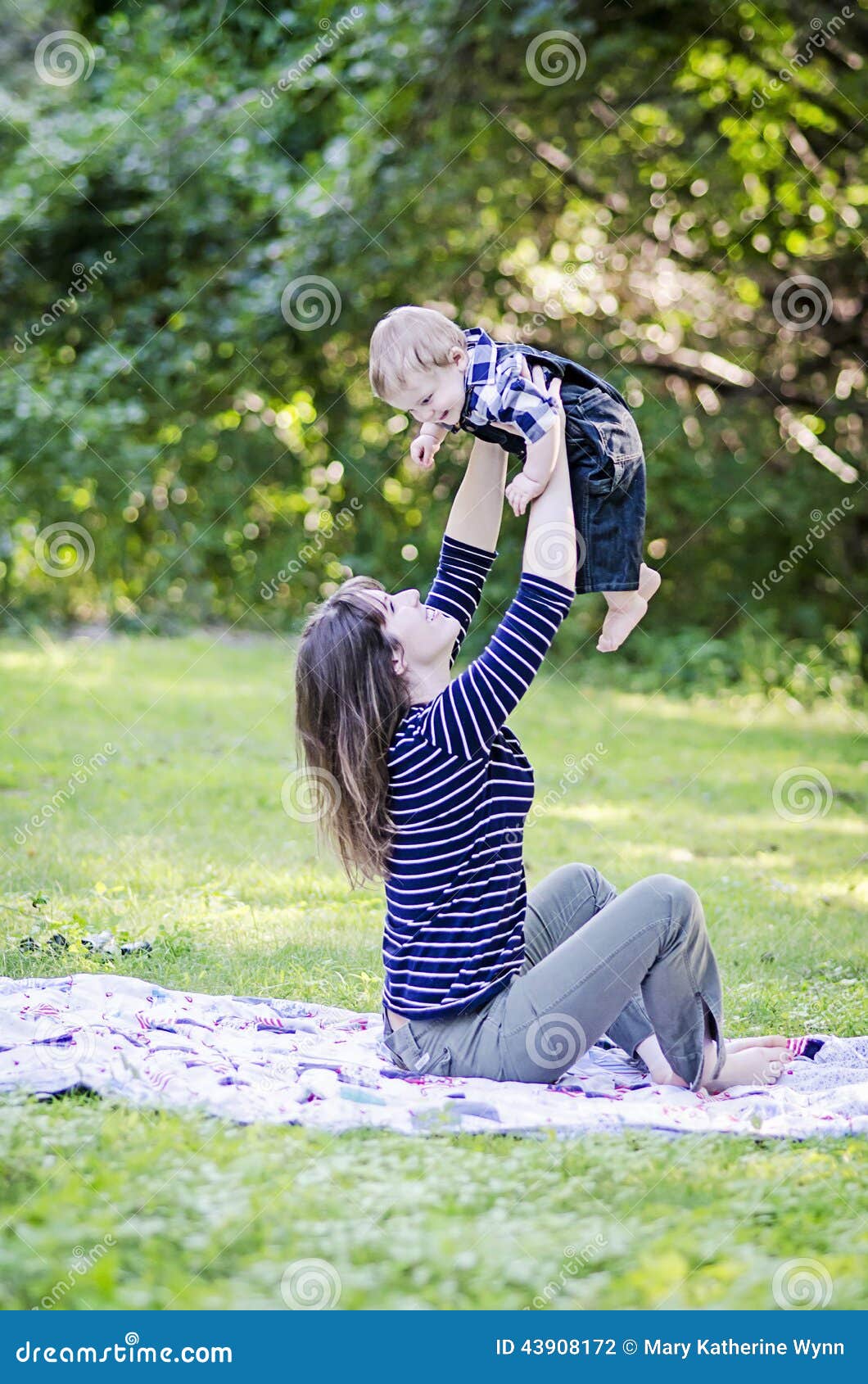 Madre y bebé feliz. Bebé sonriente que es levantado para arriba por su madre en el parque