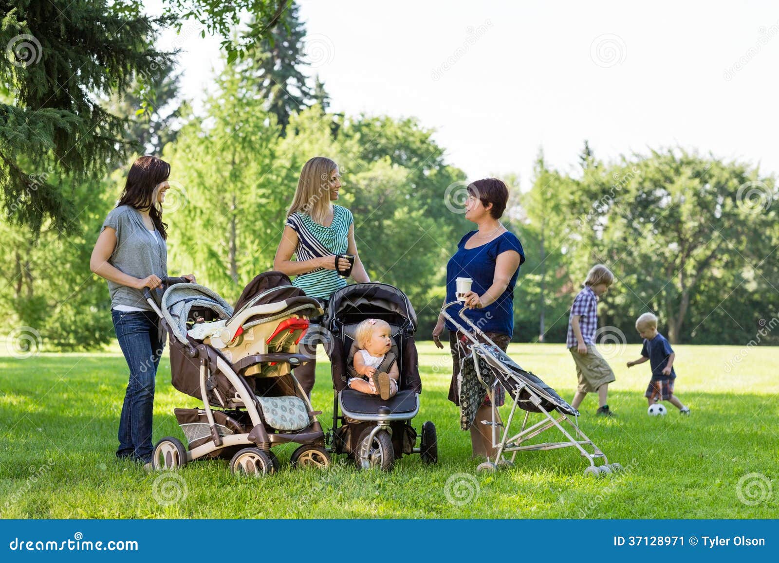 Madri felici con i passeggiatori di bambino che parlano nel parco