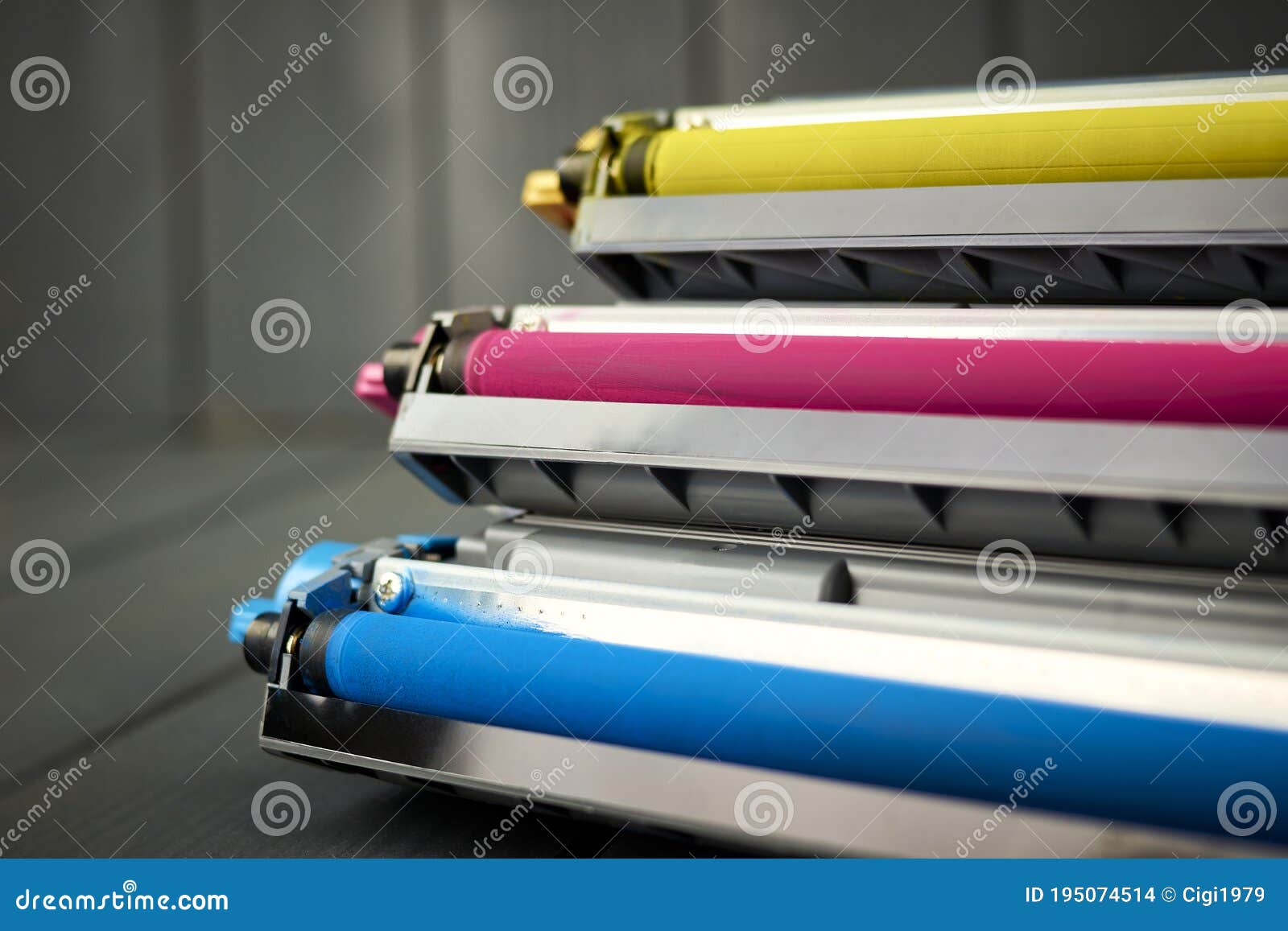 magenta, cyan and yellow toner for color laser printers stacked on gray wooden background