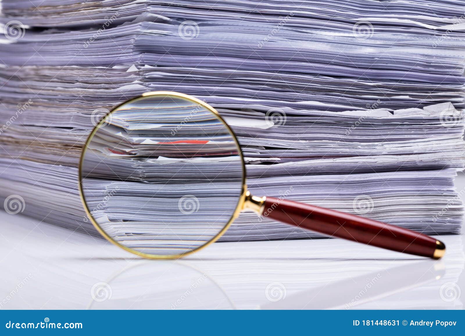 Magnifying Glass on the Background of the Stacked Paper Files Stock