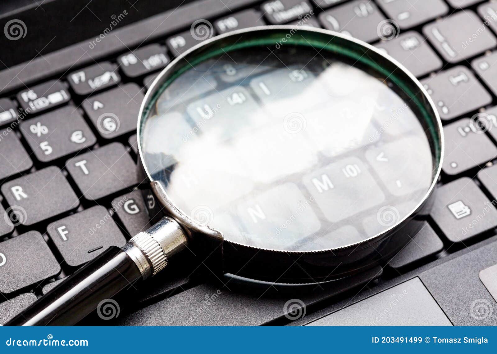 magnifying glass laying on a laptop keyboard. loupe on a netbook keys.technology file search tool concept, data forensics