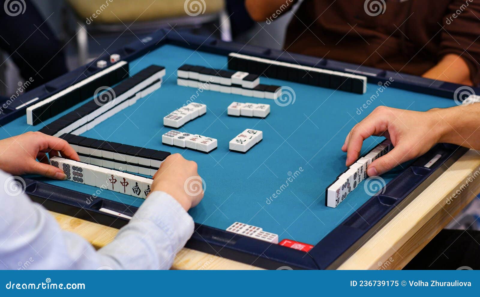 a mahjong table with an active game and the hands of the participants in the game.