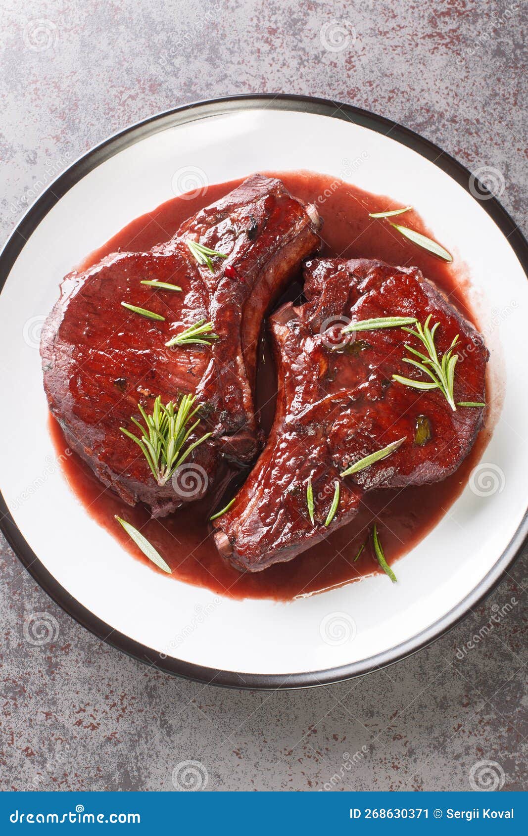 maiale ubriaco drunken pork chops in red wine sauce with herbs closeup on the plate. vertical top view