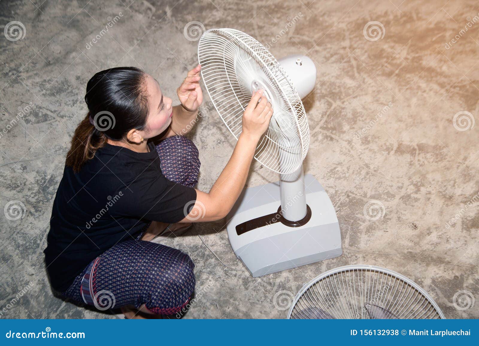 The Maid is Assembling and Installing an Electric Fan after Cleaning