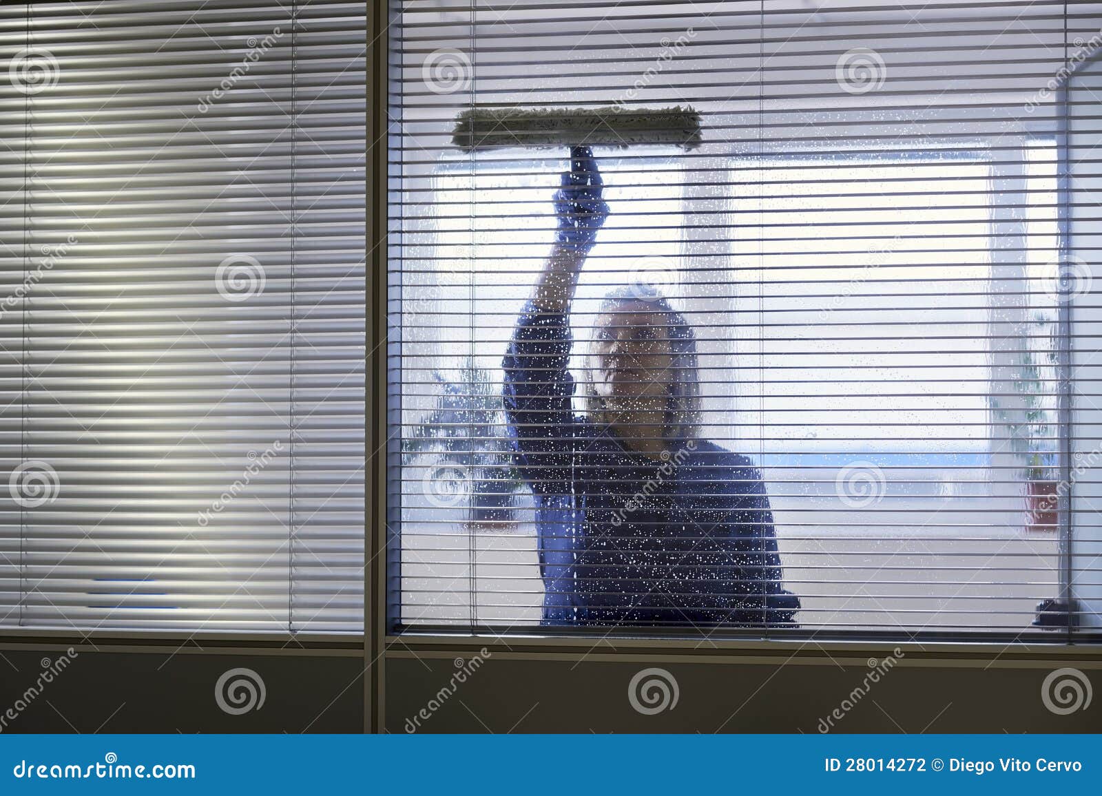 maid cleaning and wiping window in office