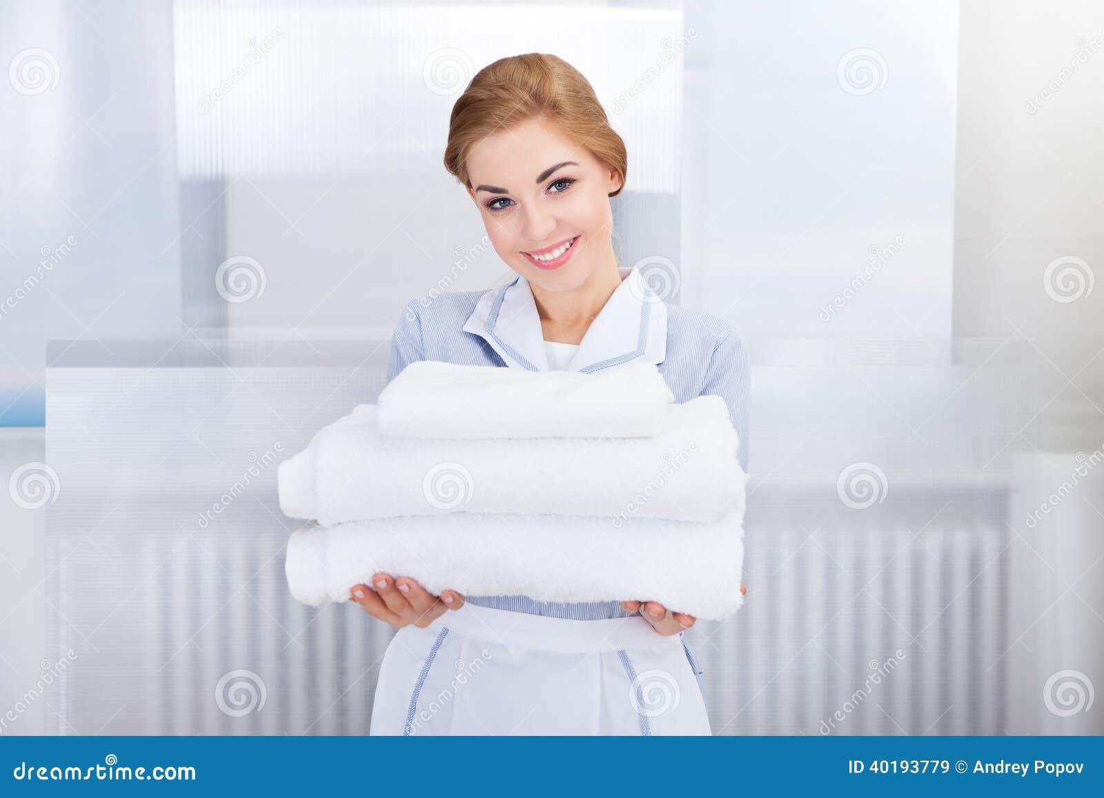 maid holding stack of towels