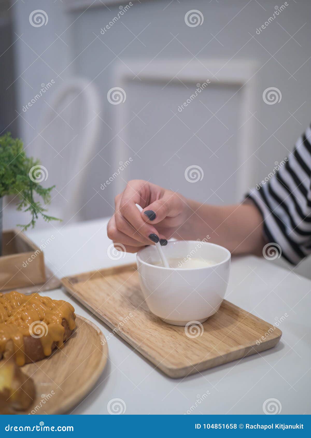 Main de femme stiring le lait chaud. Main de femme tenant la cuillère pour remuer le lait chaud