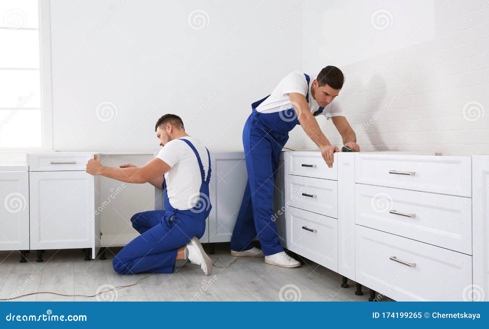 Maintenance Workers Installing New Kitchen Furniture Indoors Stock