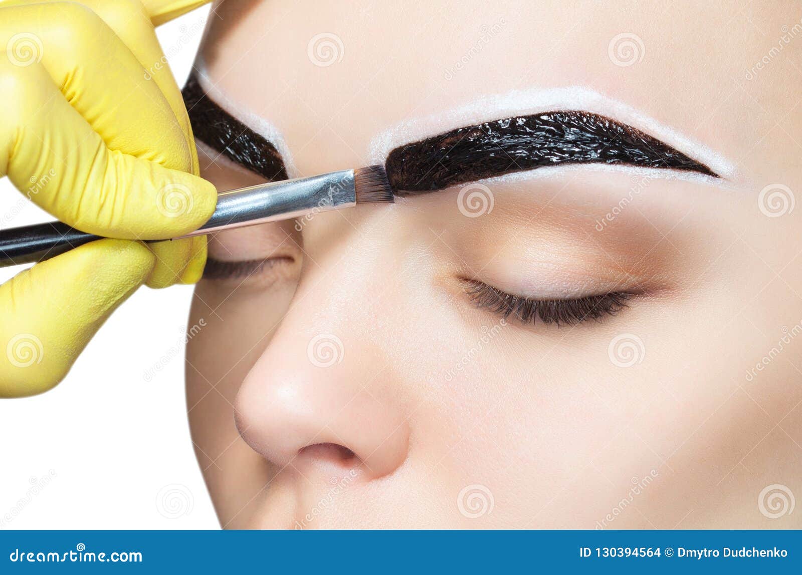 the make-up artist applies a paints eyebrow dye on the eyebrows of a young girl