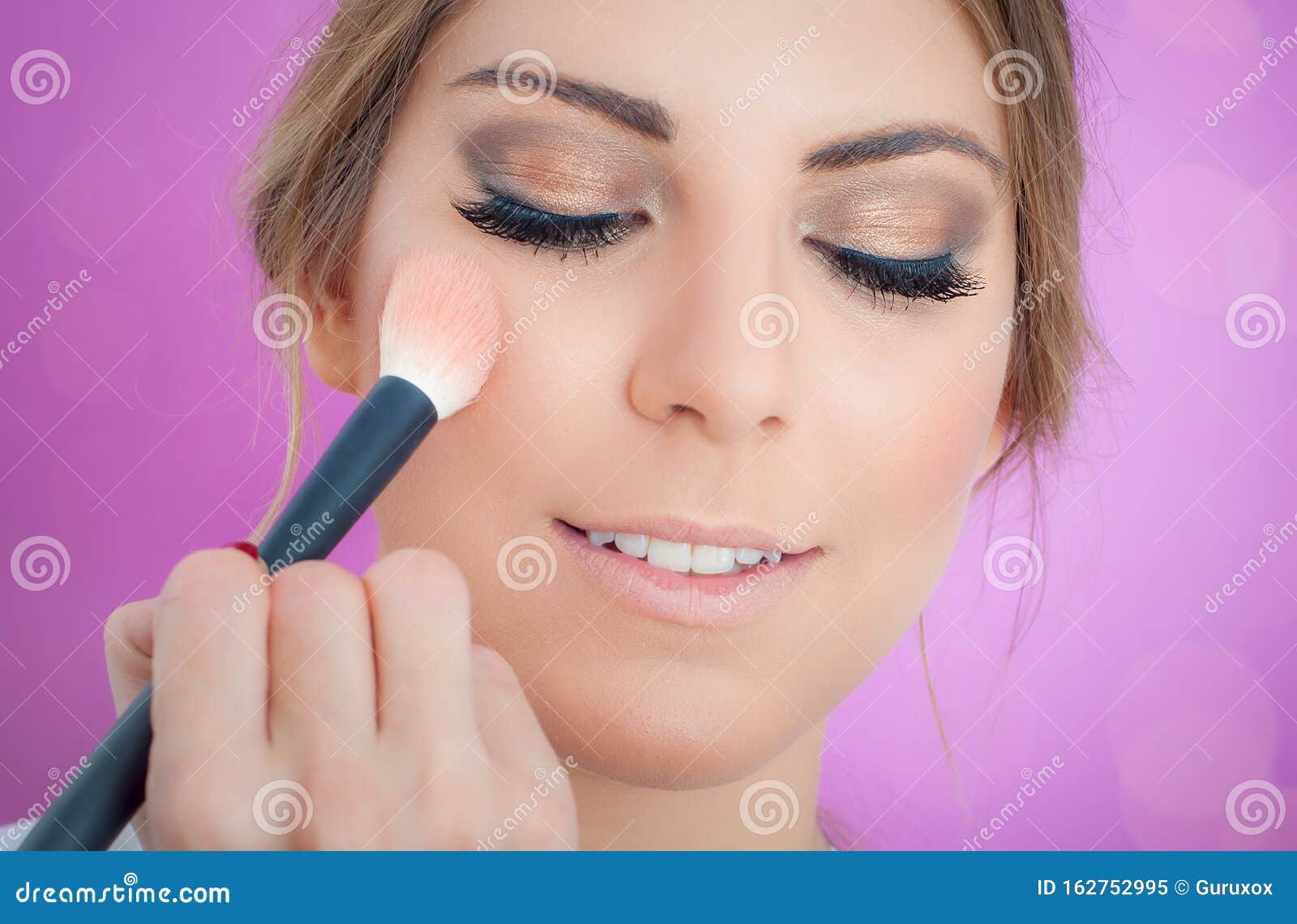 Makeup Artist Applying Makeup on Her Face Using Powder Brush Stock