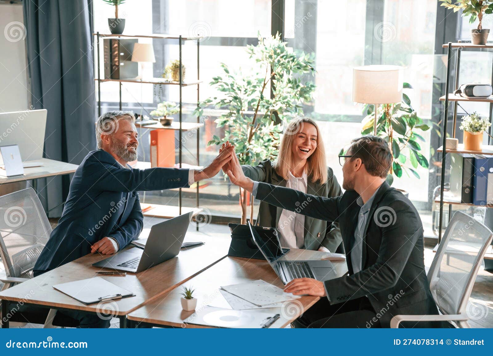 Making High Five, Sitting by the Table. Group of Business People are