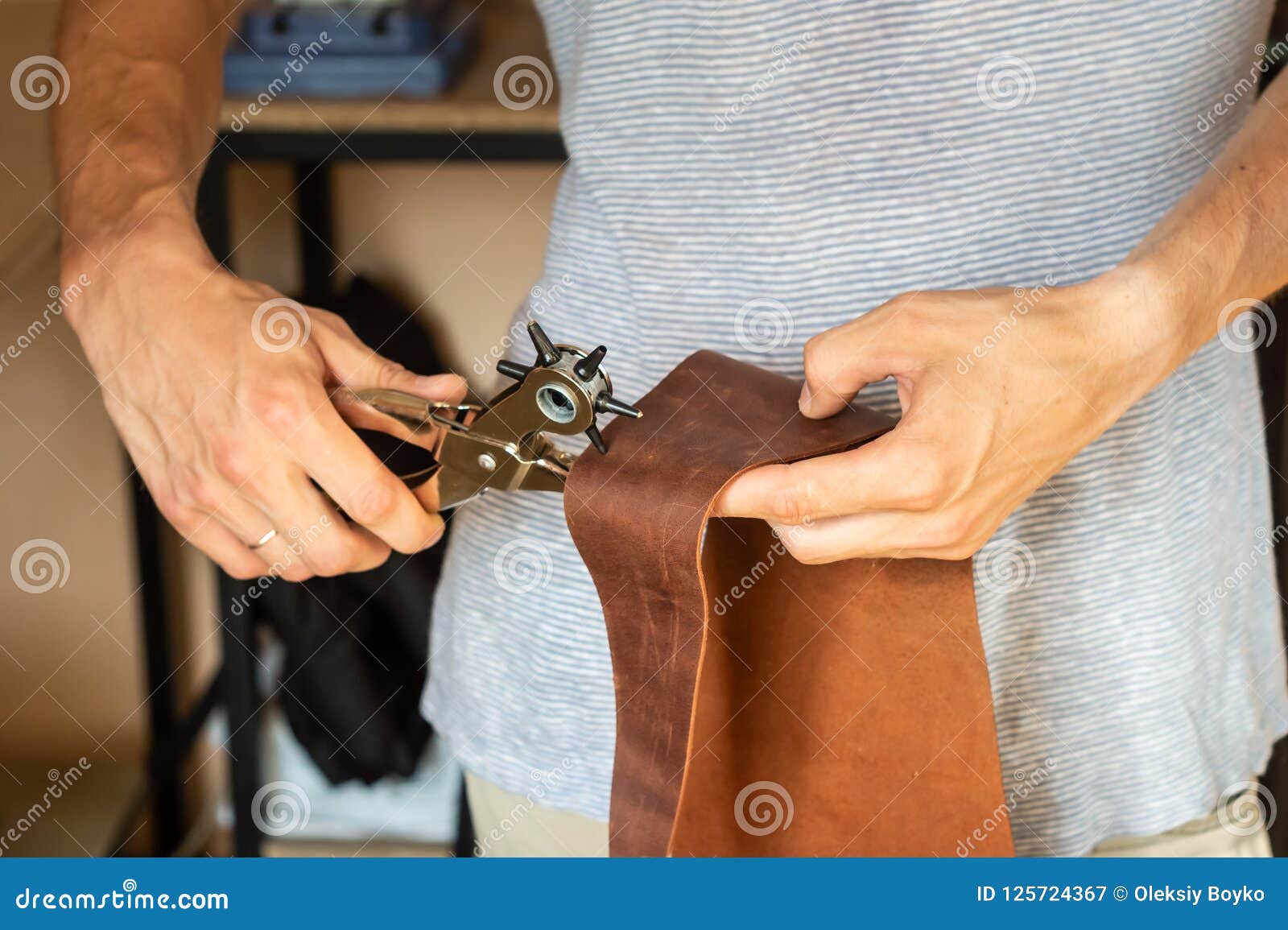 Making Holes with Puncher in Leather Male Hands with E Stock