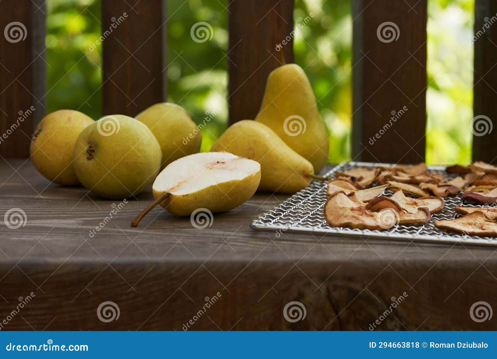 making pear chips. fresh pears and pear slices on a wire rack from a dehydrator on a wooden table.