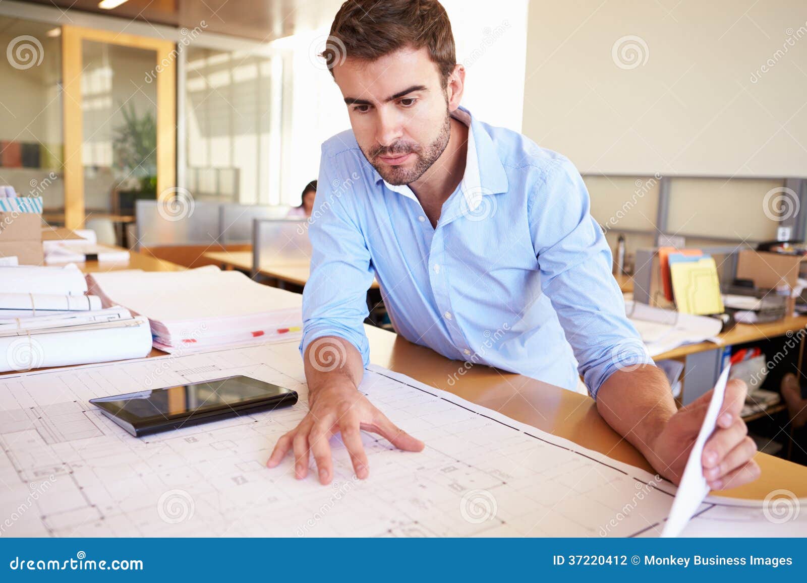 male architect with digital tablet studying plans in office