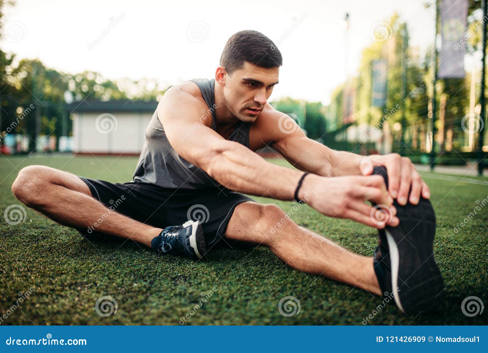 Muscular shirtless man workout with kettlebells in L Sit position outdoors.  Stock Photo