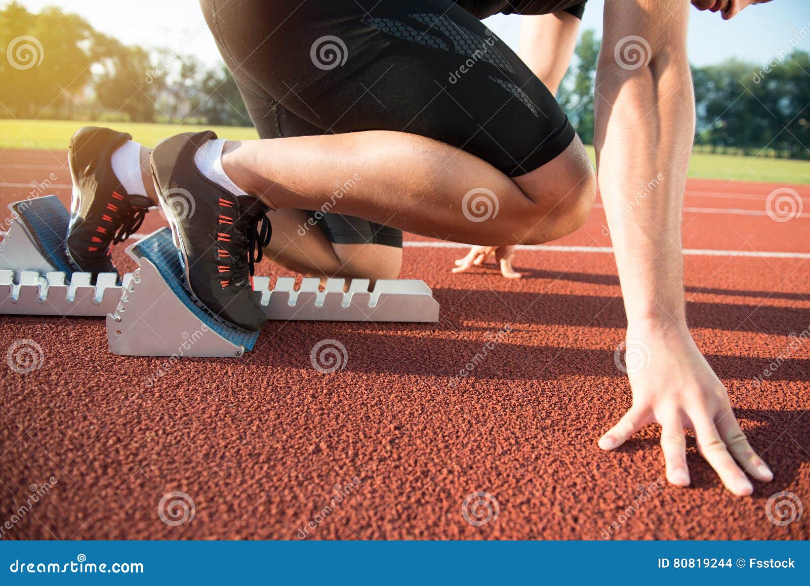 male athlete on starting position at athletics running track.