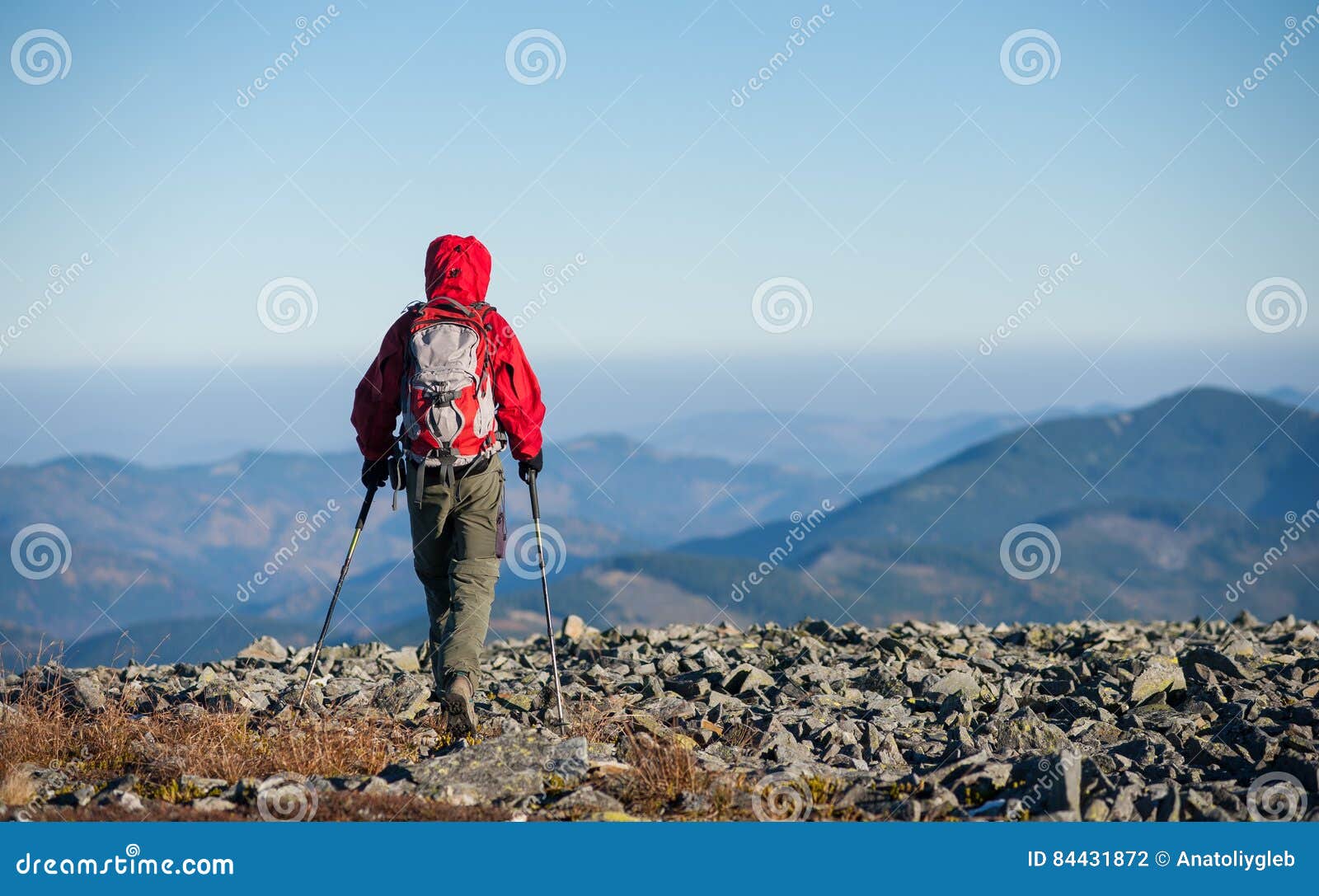 male backpaker walking on the rocky top of the mountain