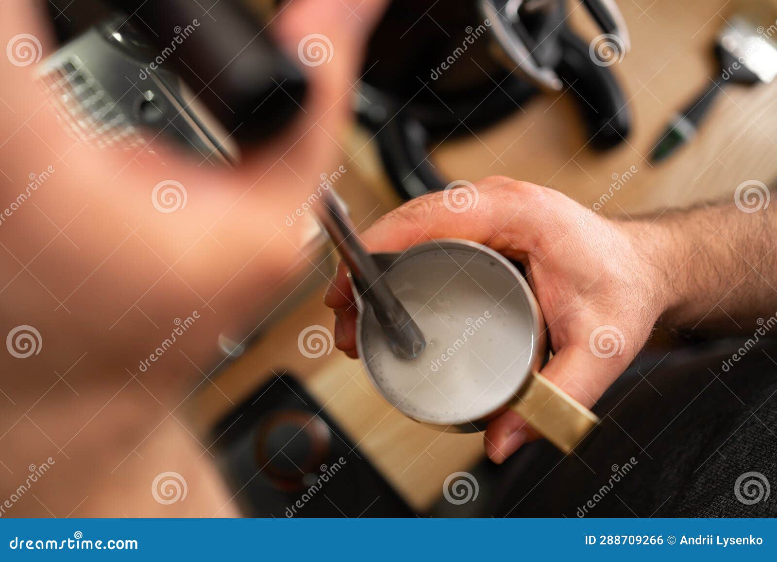 male barista froths milk on a coffee machine for making cappuccino or latte. concept of making drinks from natural