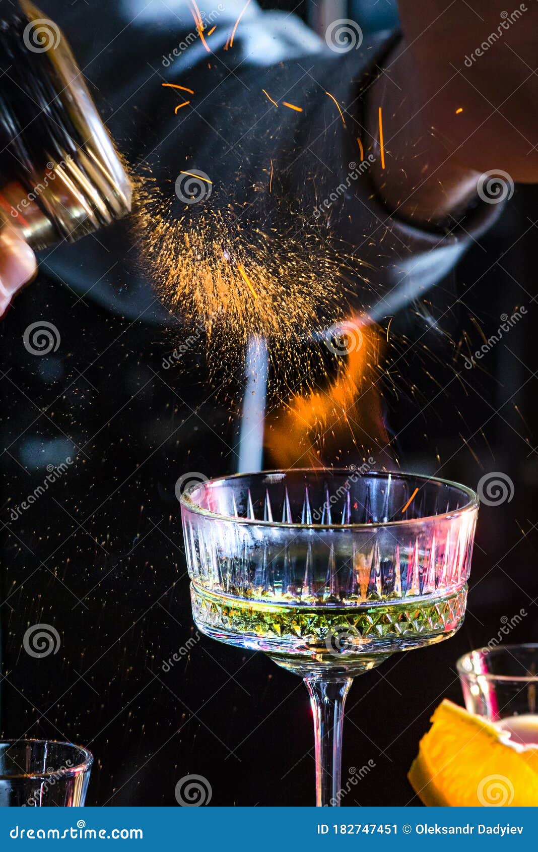 male bartender holds fired up sugar above delicious alcohol cocktail. extream fired coctail