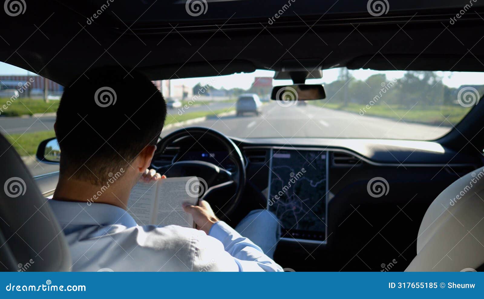 male businessperson reading book during riding on electrical vehicle with autopilot at urban road. successful