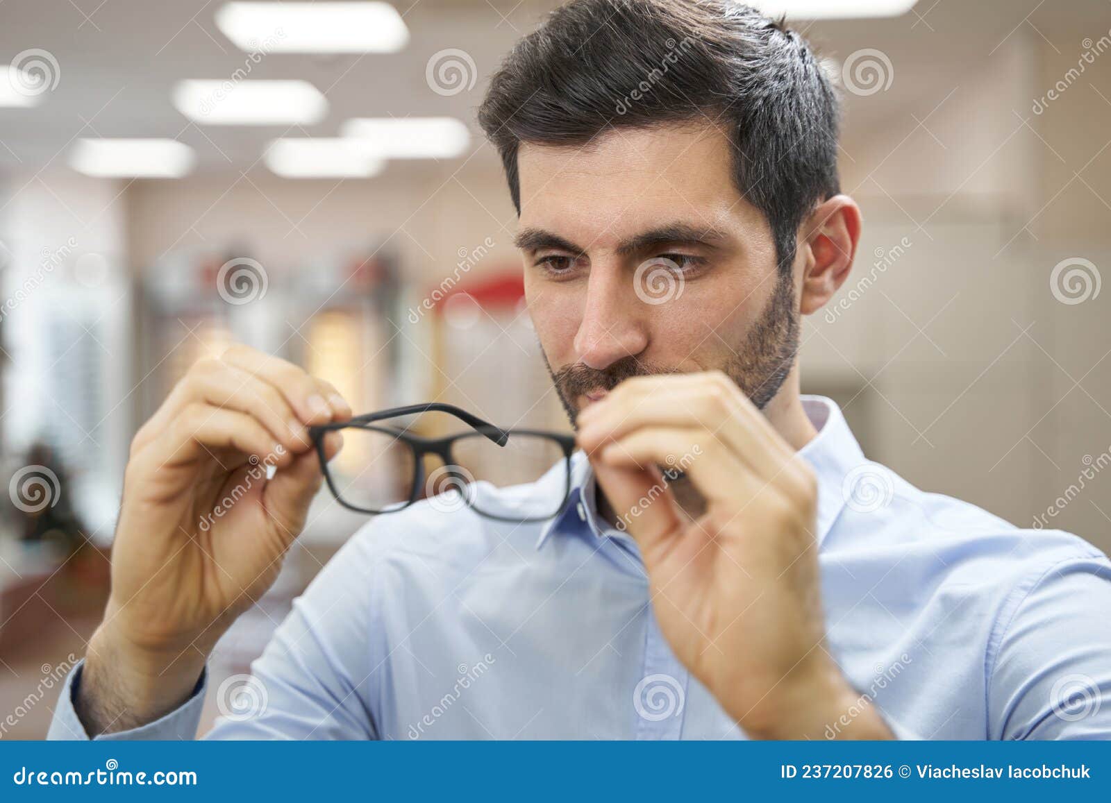 Male Buyer in Optician Shop Inspecting Pair of Glasses Stock Photo ...