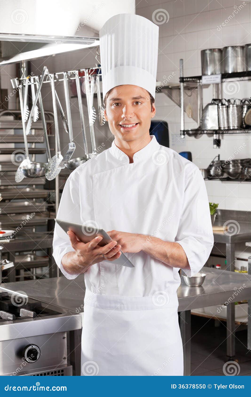 Portrait of young male chef with digital tablet in restaurant kitchen