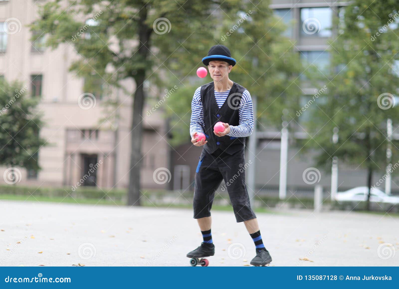 a male clown juggles with red balls
