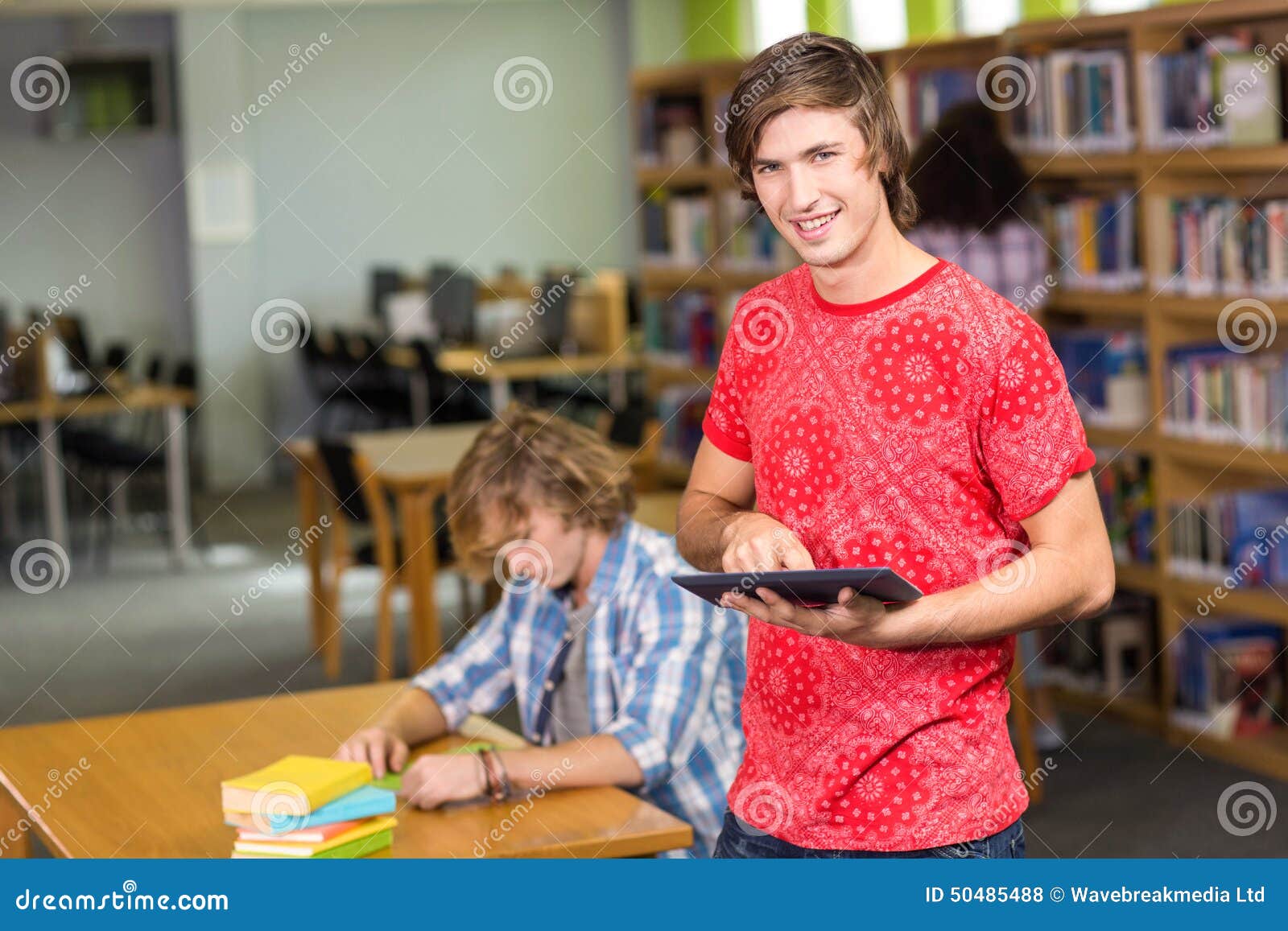 Male College Student Using Digital Tablet in Library Stock Photo