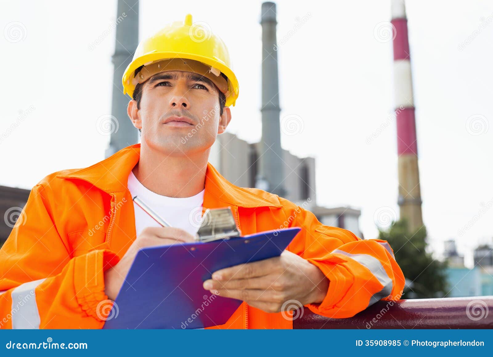 Male Construction Worker Writing on Clipboard at Industry Stock Image