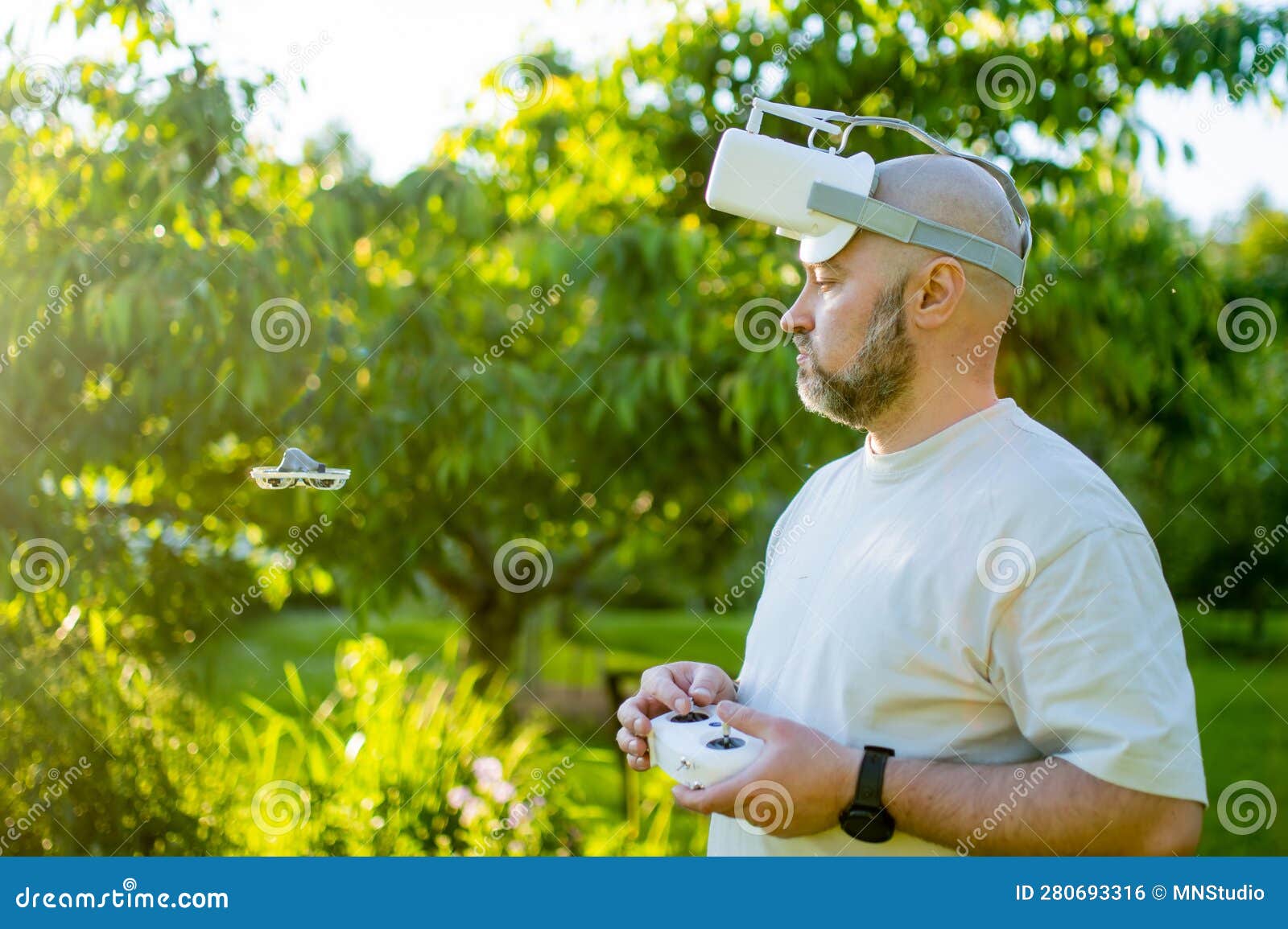 male drone pilot operating tiny whoop fpv drone in the back yard. fpv experience with fpv glasses during sunset time