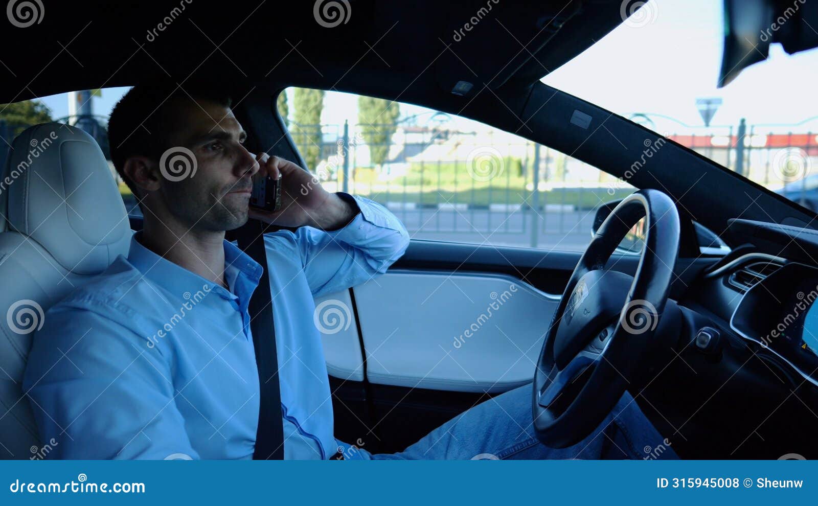 male entrepreneur speaking by smartphone during riding on electrical auto with autopilot at urban road. confident