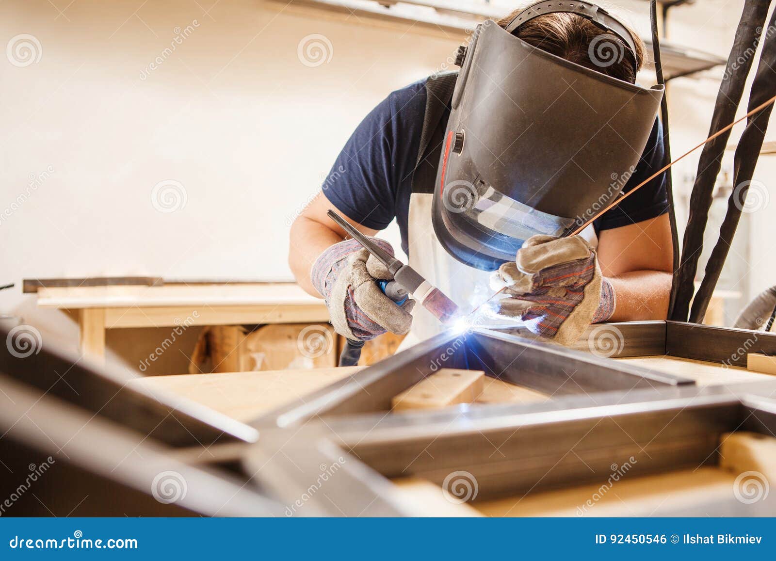 male in face mask welds with argon-arc welding