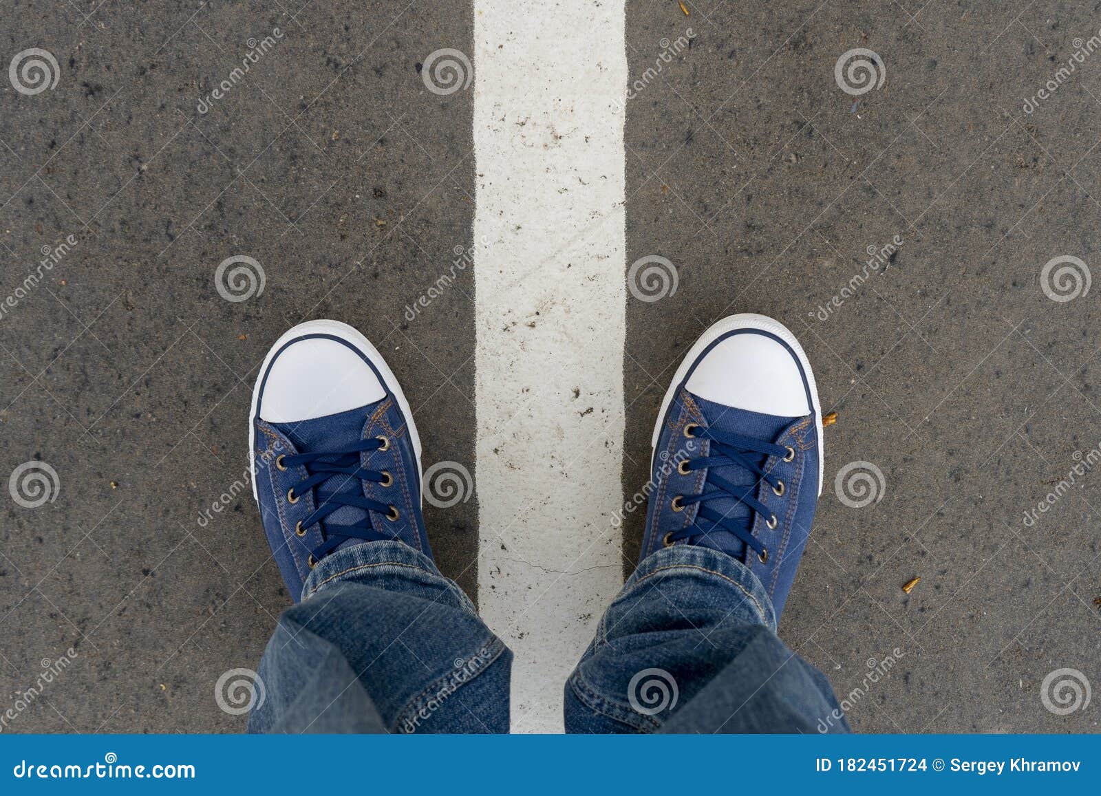 Male Feet in Blue Jeans and Blue Sneakers Shoes Stand on Street Asphalt ...
